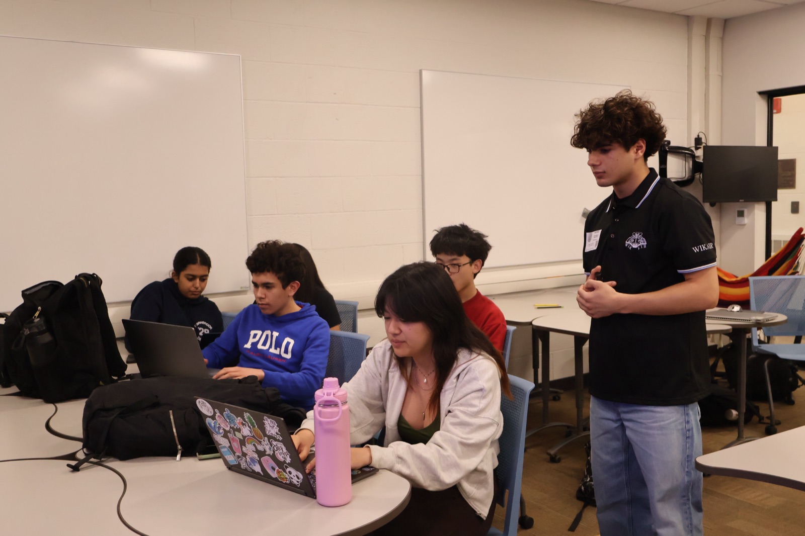 A Wikair volunteer guiding students working on laptops in a classroom